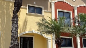 A two-story building with a yellow facade, a red accent wall, and a tiled roof.