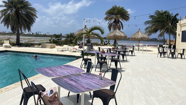 A poolside area with lounge chairs, a table, and a sign indicating pool closure times.