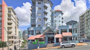 A multi-story hotel with a modern design, featuring balconies and a central entrance with a red awning. - 1 Bedroom Apt - 2 Nt Min(Comfortable one bedroom apartment with city view) (Spring Hill)