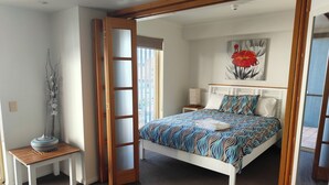 A bedroom with a bed, a nightstand, a lamp, and a vase of flowers. - 1 Bedroom Apt - 2 Nt Min(Comfortable one bedroom apartment with city view) (Spring Hill)