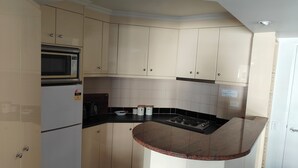 A compact kitchen with beige cabinets, a microwave, a stove, and a refrigerator. - 1 Bedroom Apt - 2 Nt Min(Comfortable one bedroom apartment with city view) (Spring Hill)