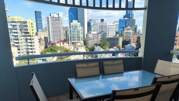 A balcony with a glass table and chairs, offering a city view. - 1 Bedroom Apt - 2 Nt Min(Comfortable one bedroom apartment with city view) (Spring Hill)