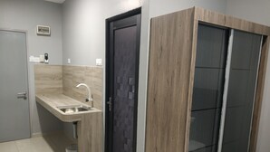 A modern bathroom with a built-in sink, a dark door, and a wooden wardrobe. - Reno Rooms Ipoh (Ipoh)