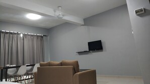 A modern living room with a flat-screen TV mounted on the wall, a ceiling fan, and a dining area with a table and chairs. - Reno Rooms Ipoh (Ipoh)