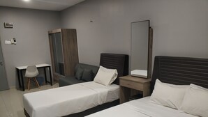 A hotel room with two single beds, a desk, a chair, a wardrobe, and a large mirror. - Reno Rooms Ipoh (Ipoh)