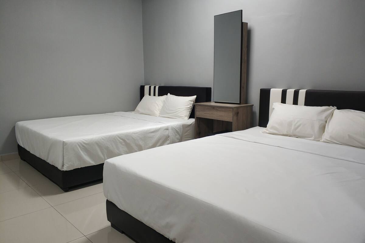 A hotel room with two beds, a nightstand, and a mirror.