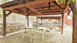 Un espacio al aire libre rústico con un porche de madera, una mesa y sillas.