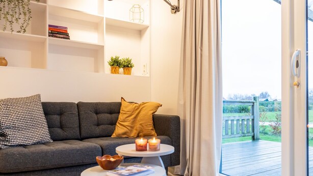 A modern living room with a grey sofa, a white coffee table, and a bookshelf.