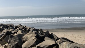 En klippefyldt kystlinje med brusende bølger der slår ind mod stranden.