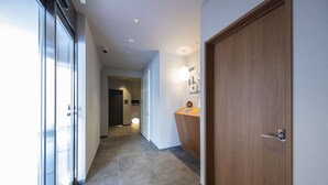 A hallway with a wooden door, a reception desk, and a glass door leading to a room.