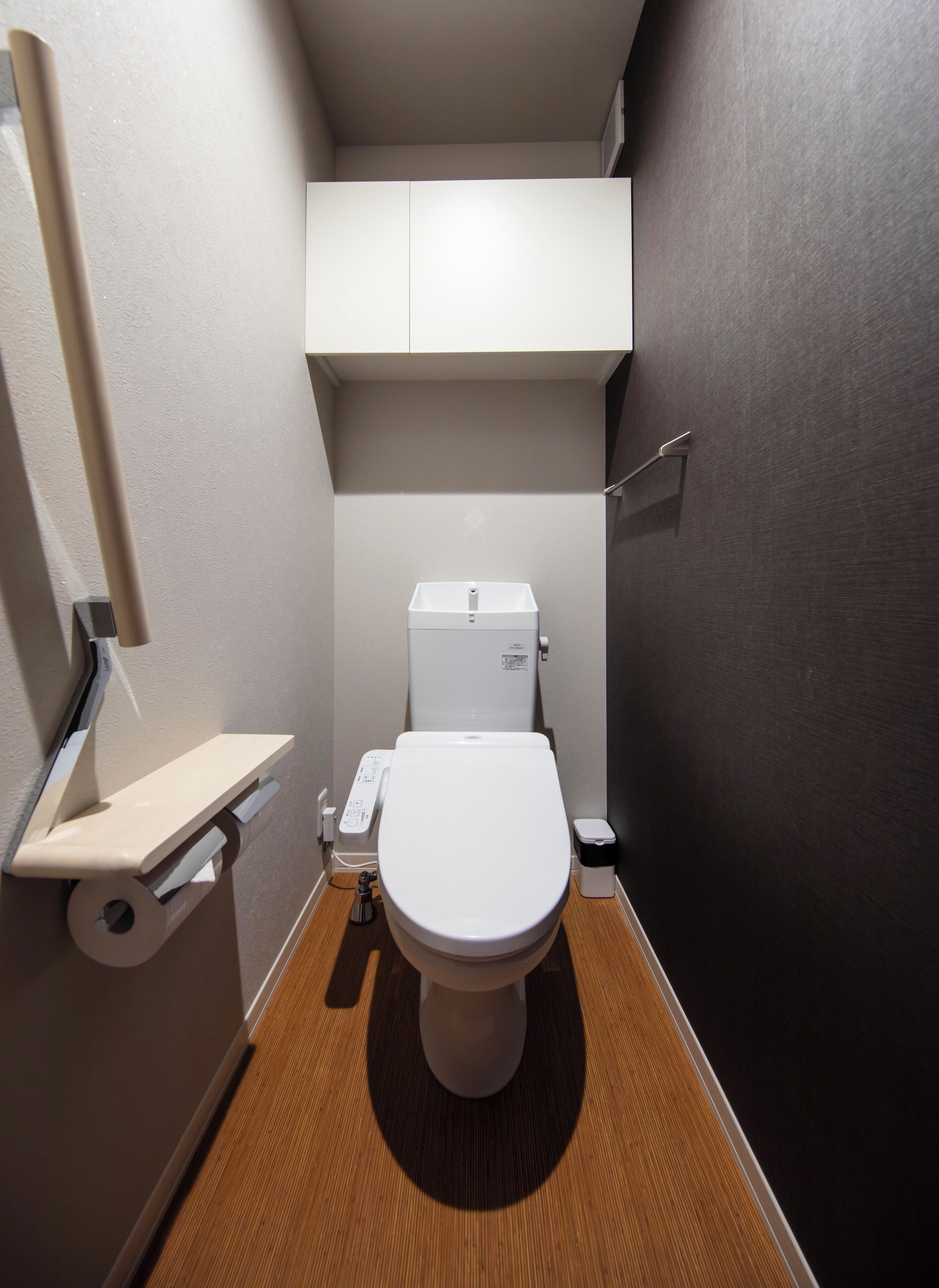 A compact bathroom with a toilet, a small shelf, and a toilet paper holder.