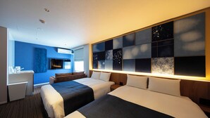 A hotel room with two beds, a desk, a TV, and a wall with a cityscape design.