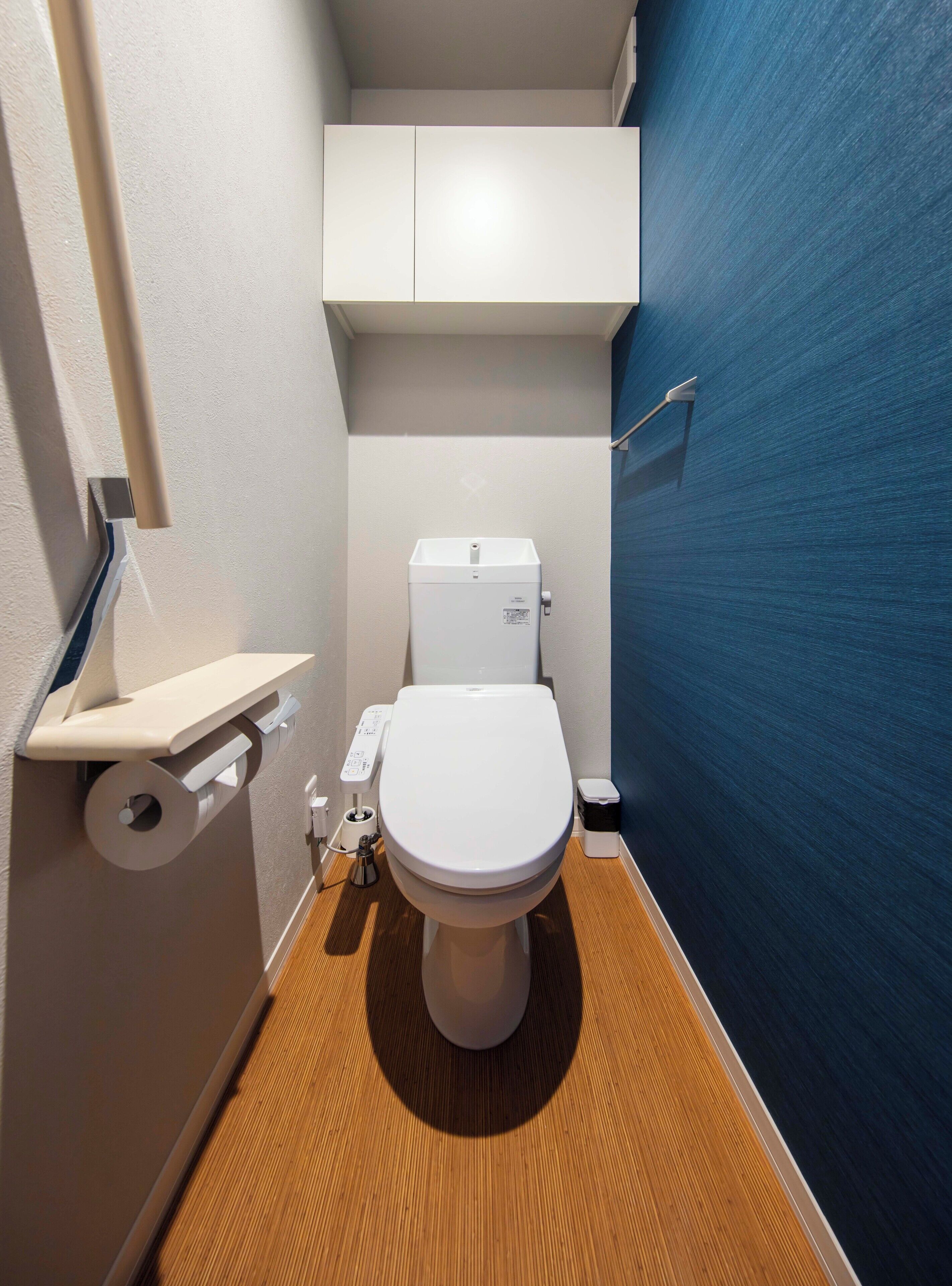 Een kleine badkamer met een wit toilet, een klein schap en een blauwe wand.