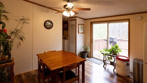 A dining area with a wooden table and chairs, a ceiling fan, and a view of the backyard through a sliding glass door. - Motorsports Basecamp near lakes and forest (Hayward)