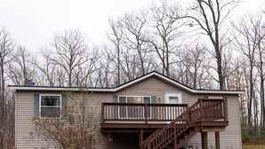 A single-story house with a front deck and a staircase leading to a covered porch. - Motorsports Basecamp near lakes and forest (Hayward)