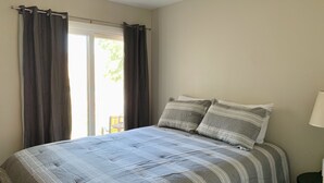 A bedroom with a bed, curtains, a window, and a lamp. - Cozy Sports Village Condo 1 BD 1 BA - Newly Remodeled! (St. George)