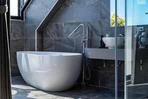 A modern bathroom with a freestanding bathtub, a glass shower enclosure, and a built-in sink.