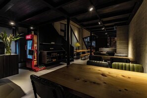 A modern interior with a wooden dining table, seating, a red Coca-Cola vending machine, and a staircase.
