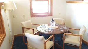 A round dining table with six chairs, a white table lamp, and a window above. - Historic Bank Building on the Elroy-Sparta State Trail (Norwalk)