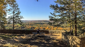 A bench in a natural setting with a view of a forested valley. - Historic Bank Building on the Elroy-Sparta State Trail (Norwalk)