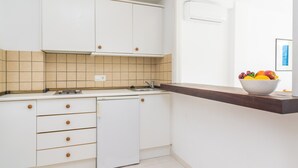 A kitchen with white cabinets, a dishwasher, a sink, and a countertop with a bowl of fruit. - MASSANET (BA) - Comfy apartment with small terrace and 250 metres from the beach Free WiFi (Capdepera)