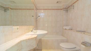 Een bad/douchecombinatie, een haardroger, handdoeken