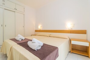 Habitació d'hotel amb un llit, dues taules de nit, un armari i llums penjades a la paret.