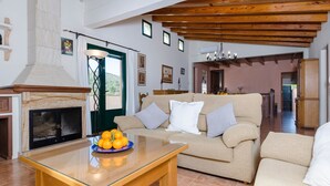 Amplia sala de estar con chimenea, un conjunto de sofás y una mesa de comedor con fruta.