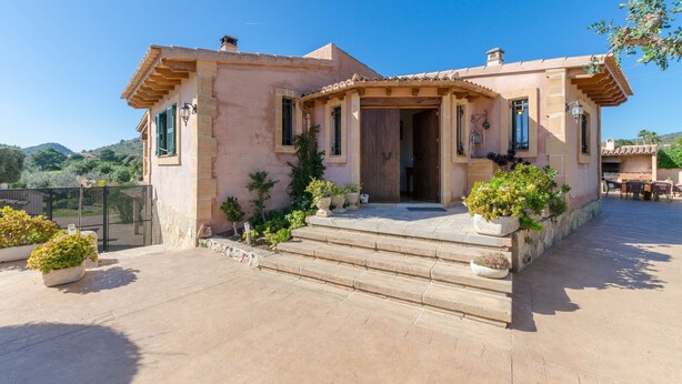 Una casa de estilo mediterráneo con fachada de piedra, puerta de madera y techo de tejas.