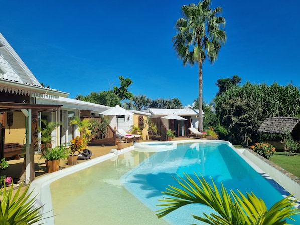 Una piscina al aire libre, sillones reclinables de piscina