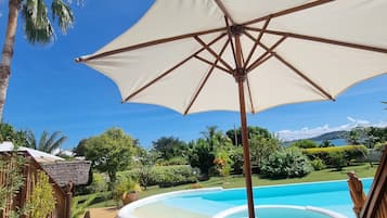 A poolside area with a lounge chair, a bench, and a large umbrella.