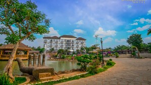 A hotel with a large building, a pond, and a stone pathway. - Spring Garden Hotel (Long Khánh)