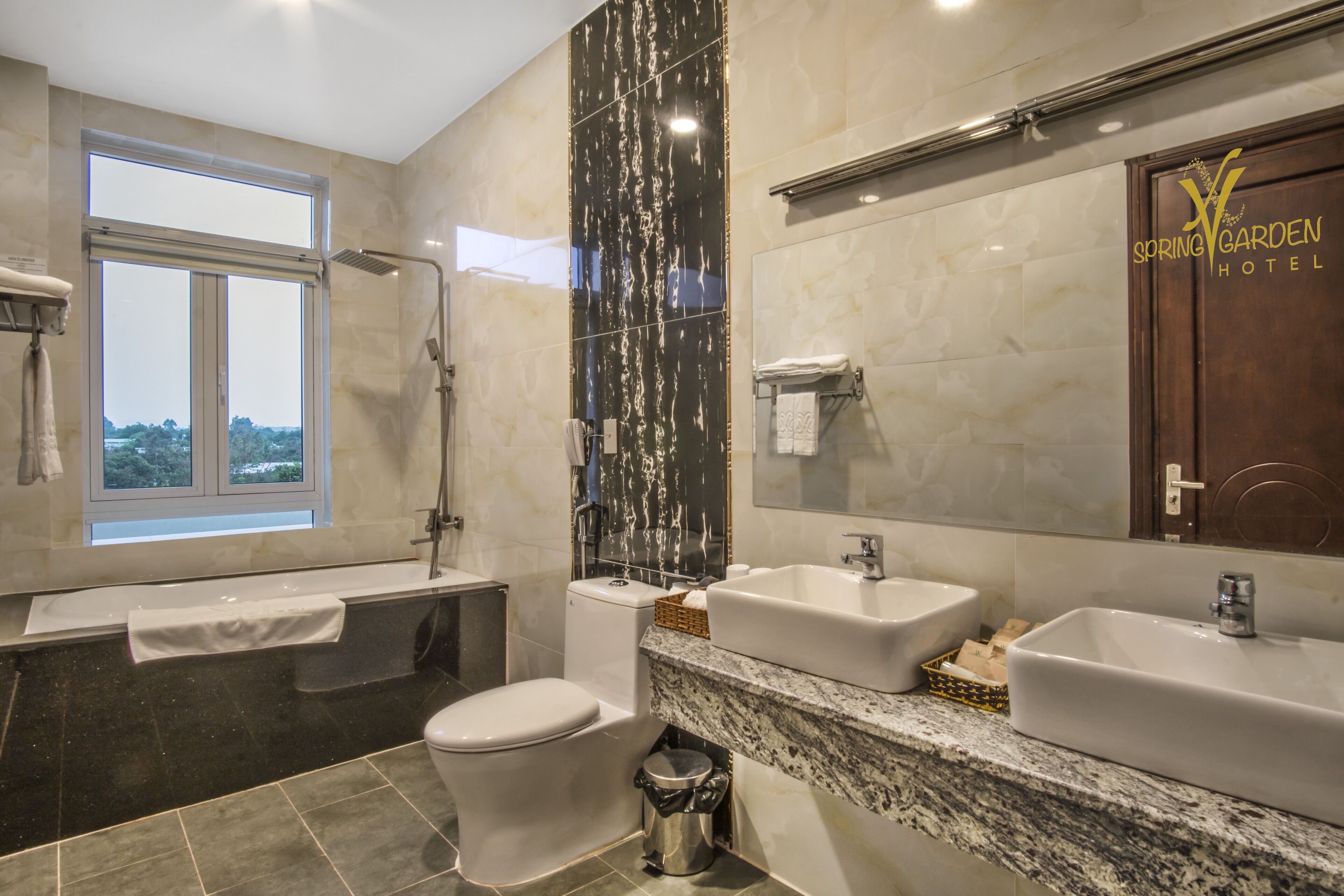 A modern bathroom with a bathtub, a toilet, and two sinks.