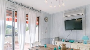 Un comedor con una mesa de madera, sillas y un televisor montado en la pared.
