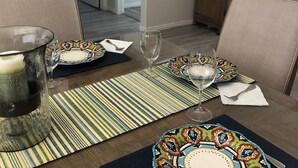 Un coin repas avec une table dressée pour deux personnes, agrémenté de vaisselle à motifs et d’un set de table rayé.