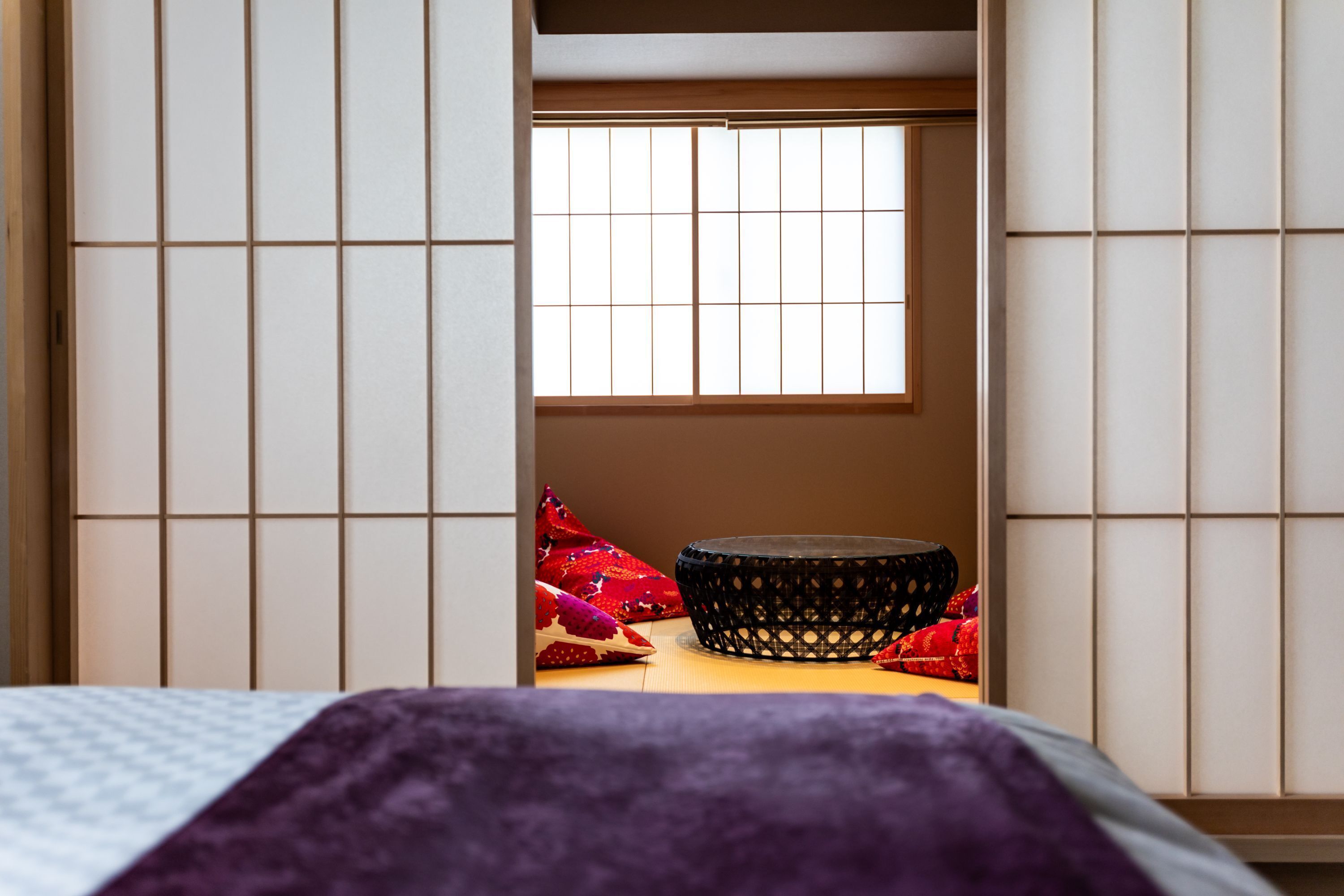 A traditional Japanese room with tatami flooring, a shoji screen, and a futon bed.