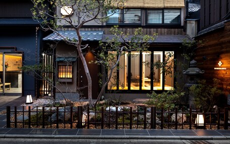A traditional Japanese house with a wooden exterior, large windows, and a well-maintained garden.