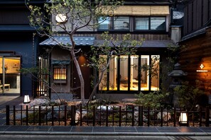 A traditional Japanese house with a wooden exterior, large windows, and a well-maintained garden. - The Machiya Ebisuya (Kyoto)