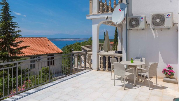 Un balcon avec vue sur la mer, des climatiseurs et du mobilier d’extérieur.