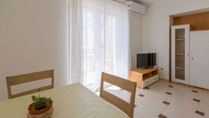 Une chambre avec un lit, une télévision, une armoire et une fenêtre avec des rideaux.