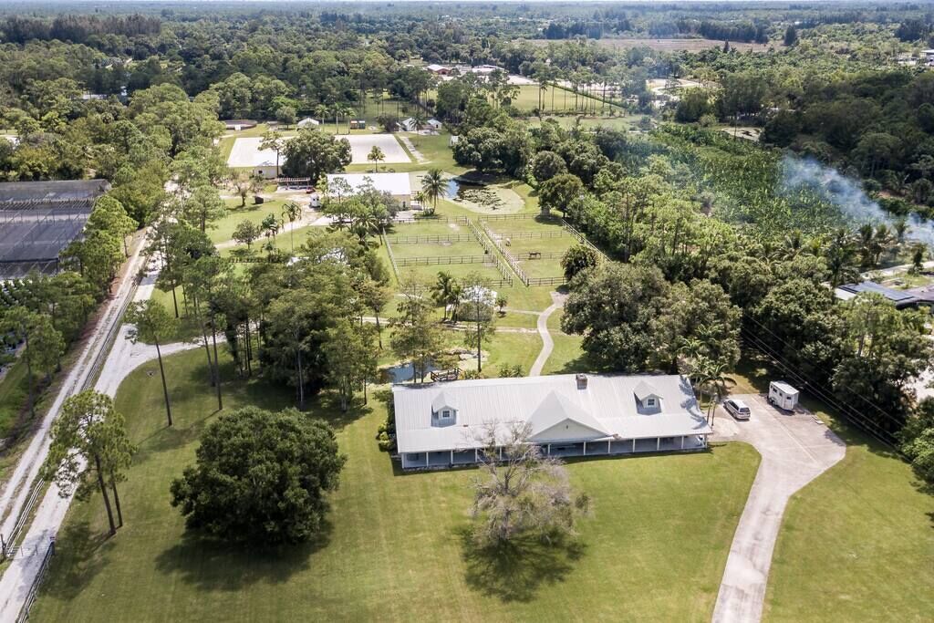 An aerial view of a large property with a central building, surrounded by green lawns and trees.