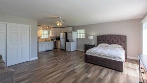 Una habitación amplia con una cama grande, un kitchenette y un ventilador de techo.