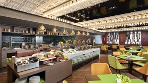 Un restaurante moderno con bufé, varias mesas para comer y una zona de cocina al fondo.