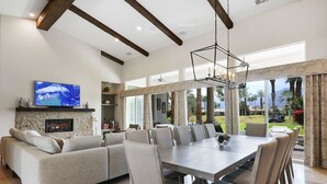 A spacious living room with a fireplace, a large TV, and a dining area with a view of the outdoors. - Casa Del Sol - Private Courtyard w/ Pool & Incredible views of PGA West. #241306 6br (La Quinta)