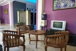Una habitación con una mesa y sillas de madera, un televisor y un calentador de agua en la pared.