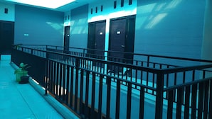A modern hotel corridor with a metal railing, a skylight, and a row of closed doors. - OYO 2654 Yulia Guesthouse Near Kopi Bajawa Flores NTT Tebet (Jakarta)
