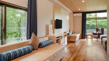 Una habitación de hotel moderna con sofá, escritorio, silla y televisor.