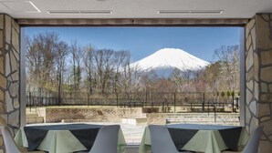 A dining area with a view of a snow-capped mountain, stone walls, and a brick pathway. - Wan Wan Paradise Premier Yamanakako (Yamanakako)