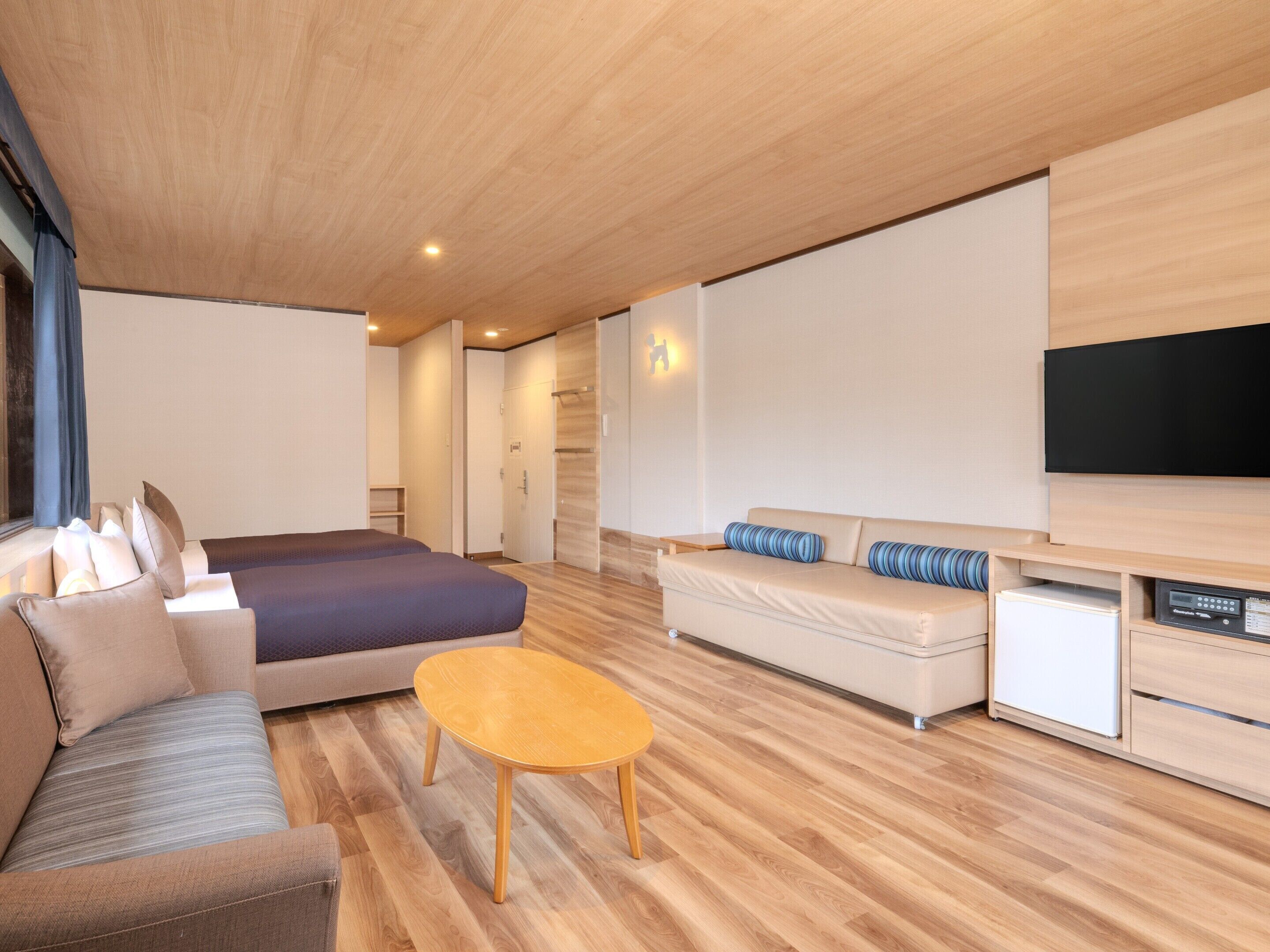 Ein modernes Hotelzimmer mit einem großen Bett, einer Couch, einem kleinen Tisch und einem flachbildfernseher an der Wand.