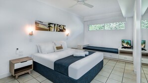 Un dormitorio moderno con una cama grande, una mesita de noche, un banco y un televisor.